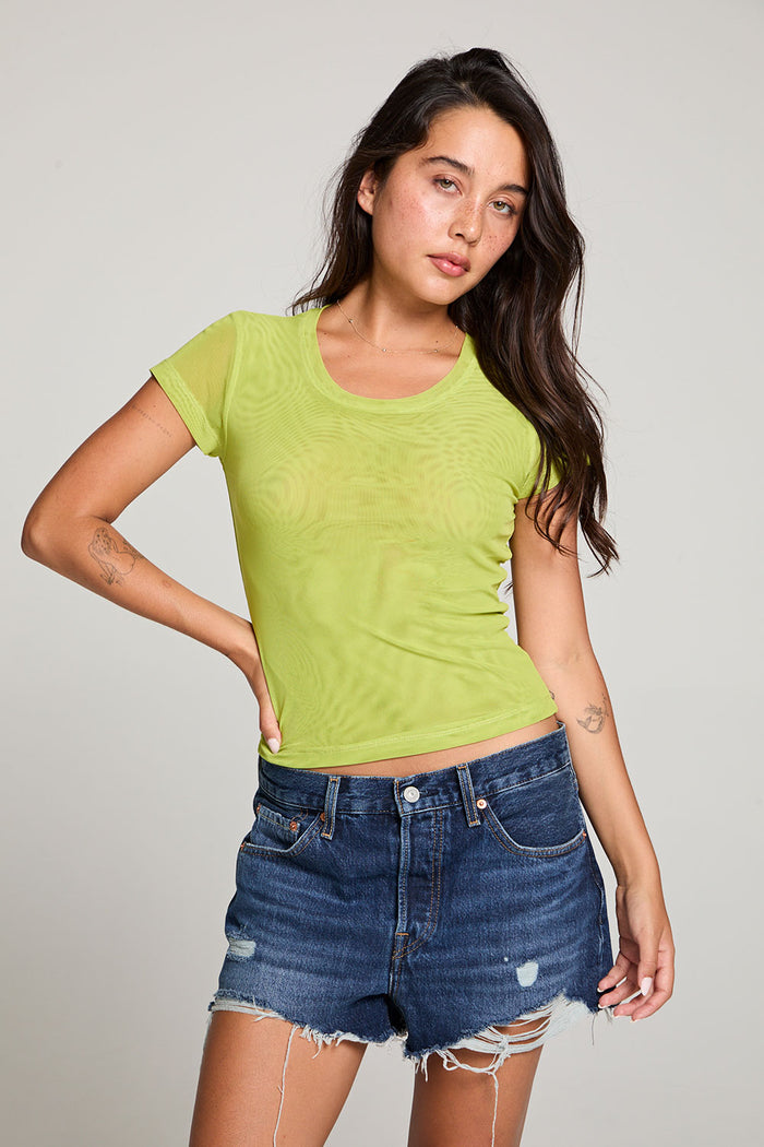 Front view of model wearing the 90’s Chartreuse Baby Tee in bright green with scoop neck and fitted cropped cut and cut off denim against a plain background