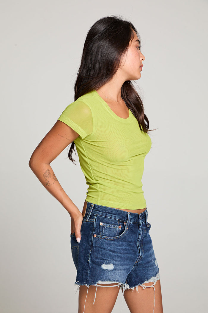 Side view of model wearing the 90’s Chartreuse Baby Tee in bright green with scoop neck and fitted cropped cut and cut off denim against a plain background