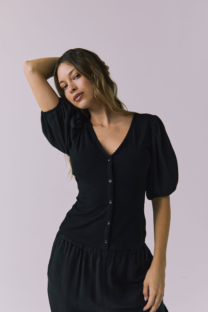 Chaser Abbie Black Blouse shown with matching Lee Trousers in a soft half body pose with the model lifting her arm