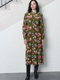 A woman wearing a green floral midi dress with a button through front, a shirt collar and a shirred waist.