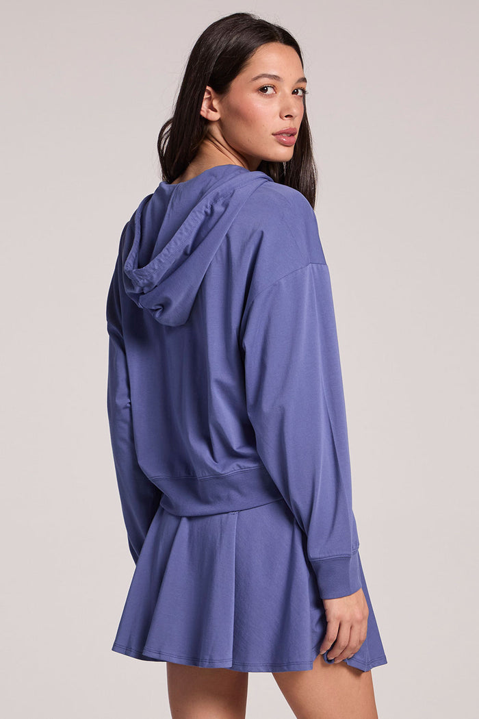 Back view of a woman wearing the Chaser French Riviera Abilena Zip-Up on a neutral background, looking over one shoulder