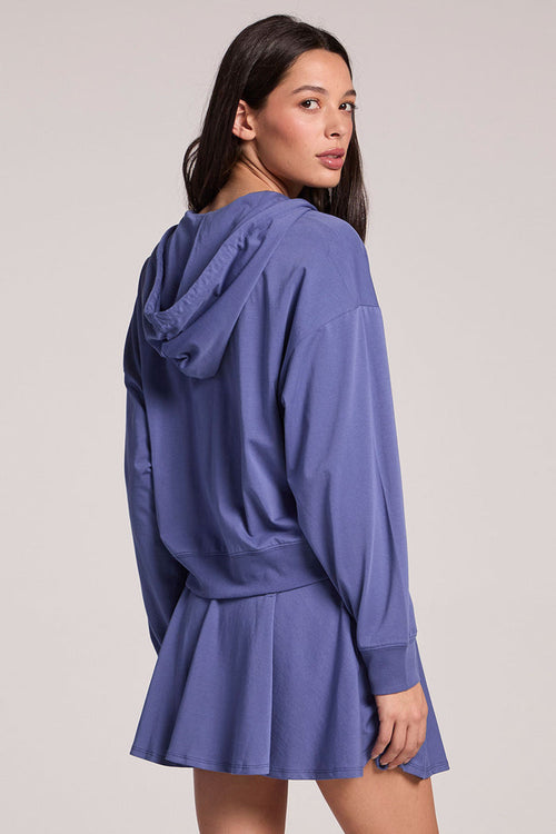 Back view of a woman wearing the Chaser French Riviera Abilena Zip-Up on a neutral background, looking over one shoulder
