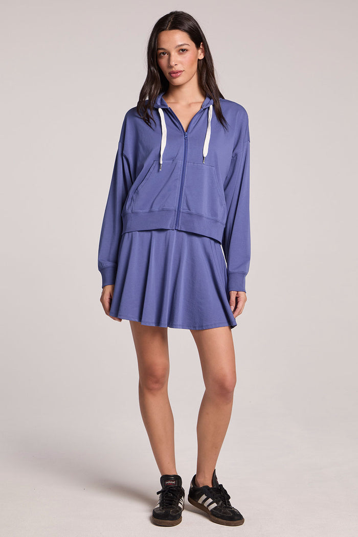 Full body view of a woman wearing the Chaser French Riviera Abilena Zip-Up and sneakers on a neutral background
