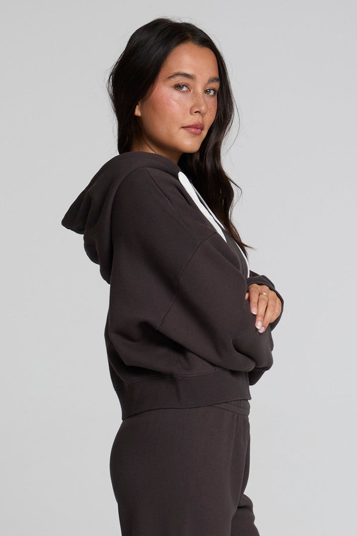Side view of a woman wearing the Chaser  Abilene Dark Heather Grey Zip Up on a neutral background with pants
