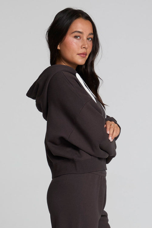 Side view of a woman wearing the Chaser  Abilene Dark Heather Grey Zip Up on a neutral background with pants