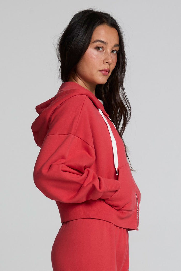 Side view of a woman wearing the Chaser  Abilene Dry Red Zip Up on a neutral background with pants