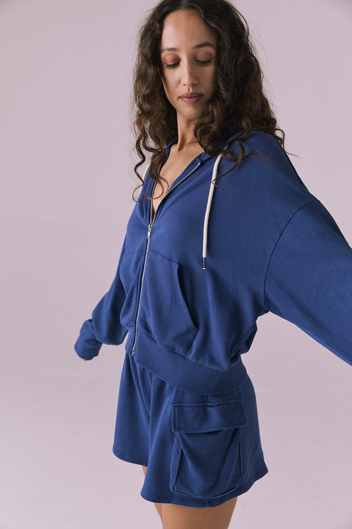 Side view of the Chaser Abilene Honest Indigo Zip Up Hoodie showing the slouchy silhouette and ribbed hem detailing