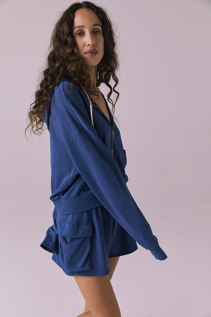Side view of the Chaser Abilene Honest Indigo Zip Up Hoodie showing the slouchy silhouette and ribbed hem detailing