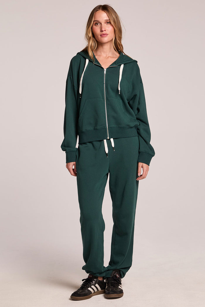 Front view of a woman wearing the Chaser  Abilene Pine Pullover and matching shoes on a neutral background