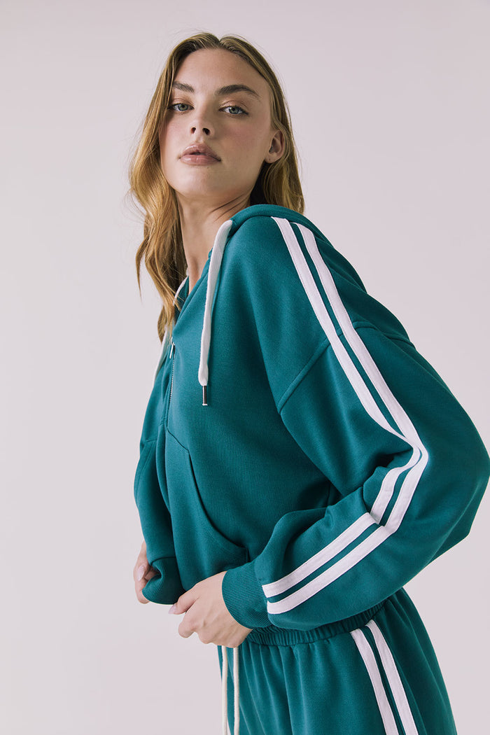 Chaser Abilenee Teal Zip Up with White Stripes in a side profile studio shot emphasizing the relaxed drape and arm stripes