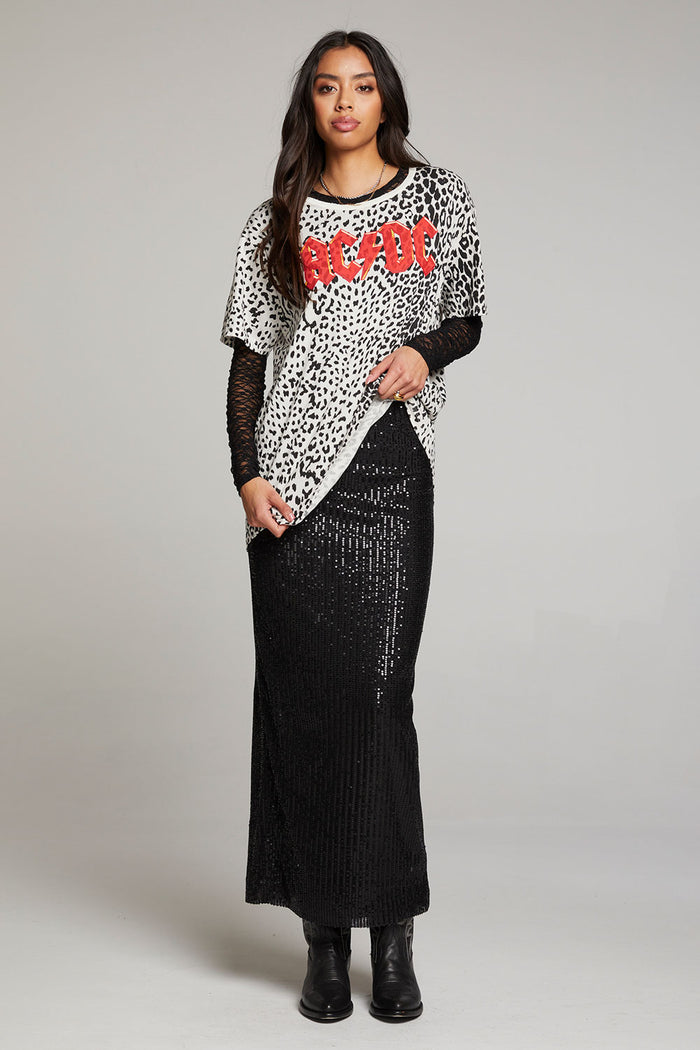 Full view of model wearing AC/DC Animal Print Logo Tee with red band logo and leopard print design with black shiny skirt and boots against a plain background