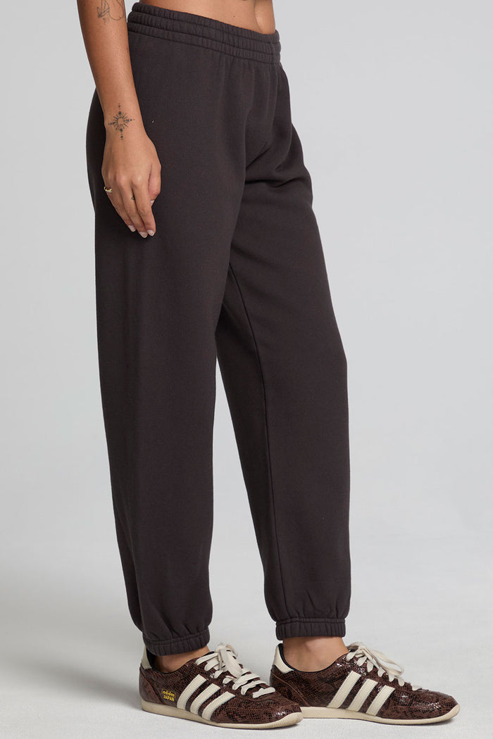 Side view of a woman wearing the Chaser Ada Dark Heather Grey Jogger on a neutral background with brown sneakers
