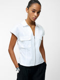 A woman wearing a white v-neck zip through top with 2 front pockets and short sleeves.