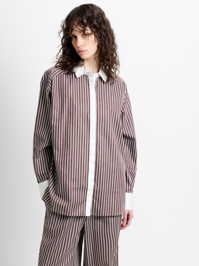 Woman wearing a brown and white striped poplin shirt with long sleeves and contrasting collar and cuffs