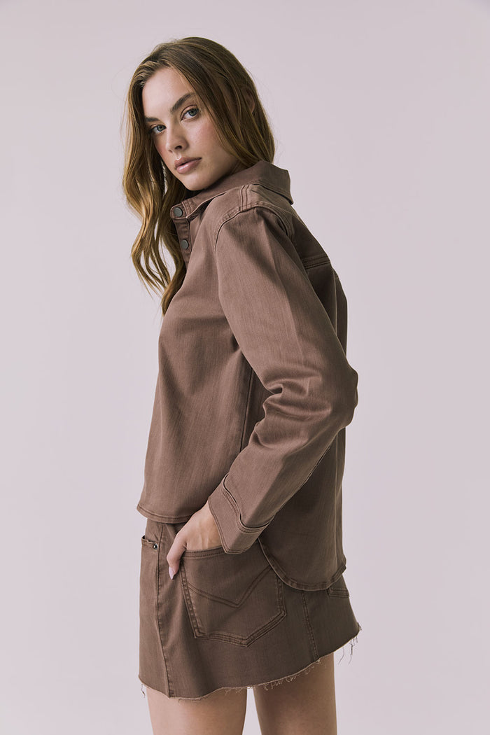 Back view of a woman wearing the Chaser brown All Day Cognac Wash Button Down with matching Sloane Mini Skirt against a plain background