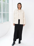 Woman wearing a black skirt and a cream boucle long sleeve overshirt