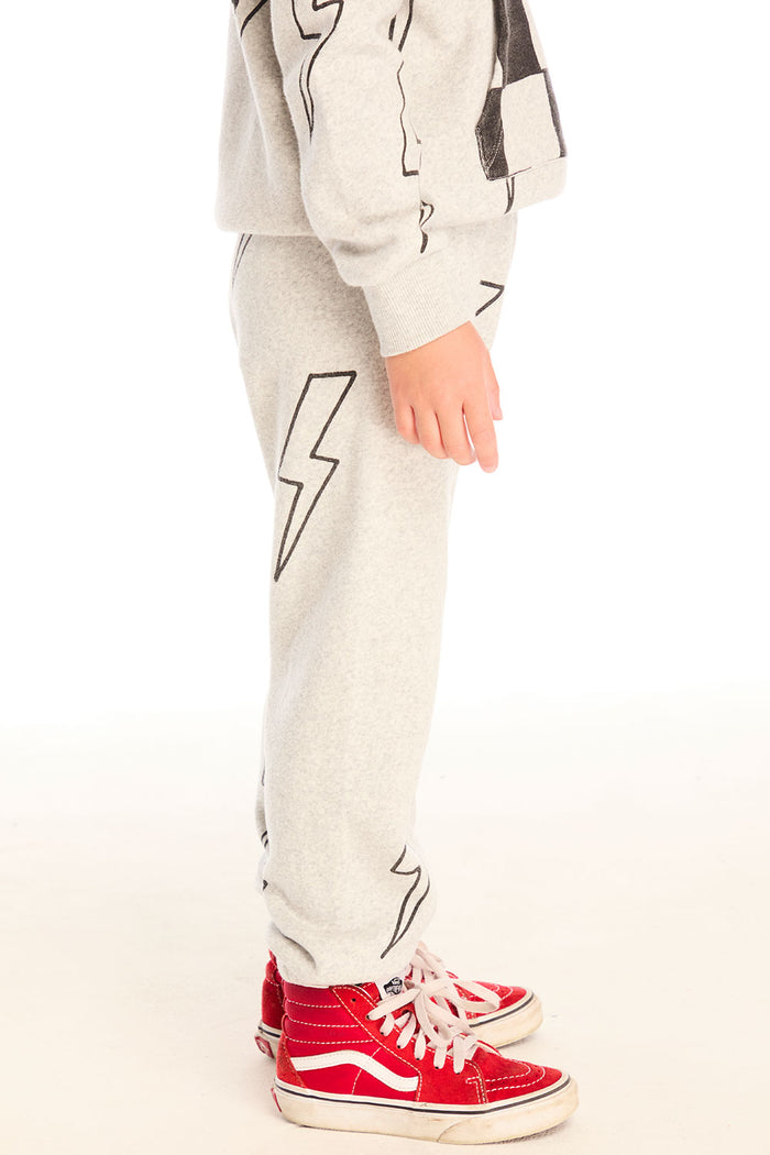 Side view of boy wearing Chaser's gray Allover Bolts pants with lightning bolt designs and on a white background