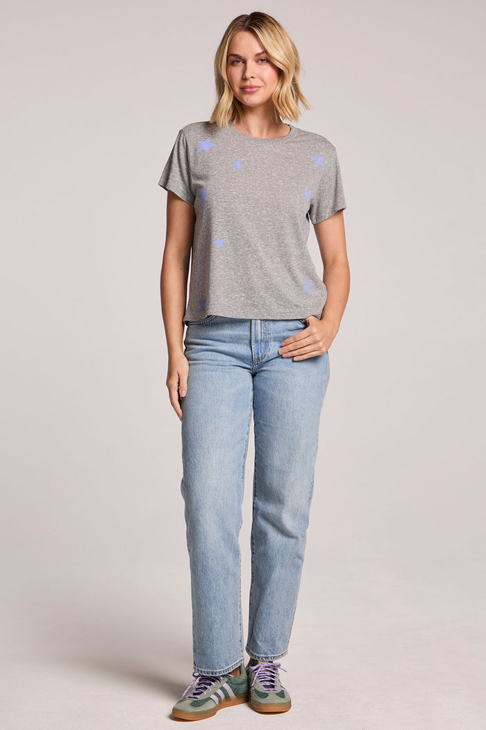 Front view of a woman wearing the Chaser  Allover Stars Tee and sneakers on a neutral background