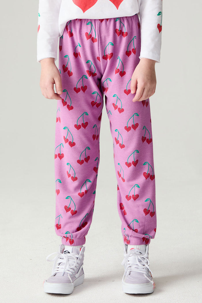 Front view of a girl wearing the Chaser Allover Sweethearts Girls Jogger on a neutral background with sneakers and shirt