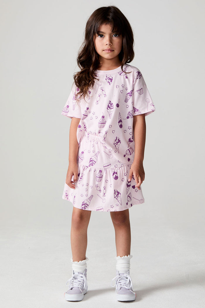 Full body front view of a girl wearing the Chaser Allover Sweets Peplum Skort  on a neutral background with matching top