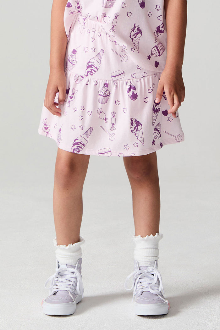 Front view of a girl wearing the Chaser Allover Sweets Peplum Skort  on a neutral background with hands at her sides