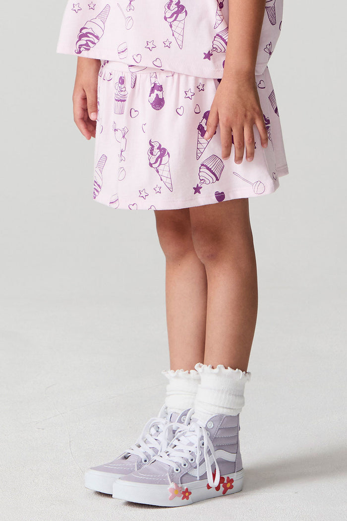 Side view of a girl wearing the Chaser Allover Sweets Peplum Skort  on a neutral background with hands down