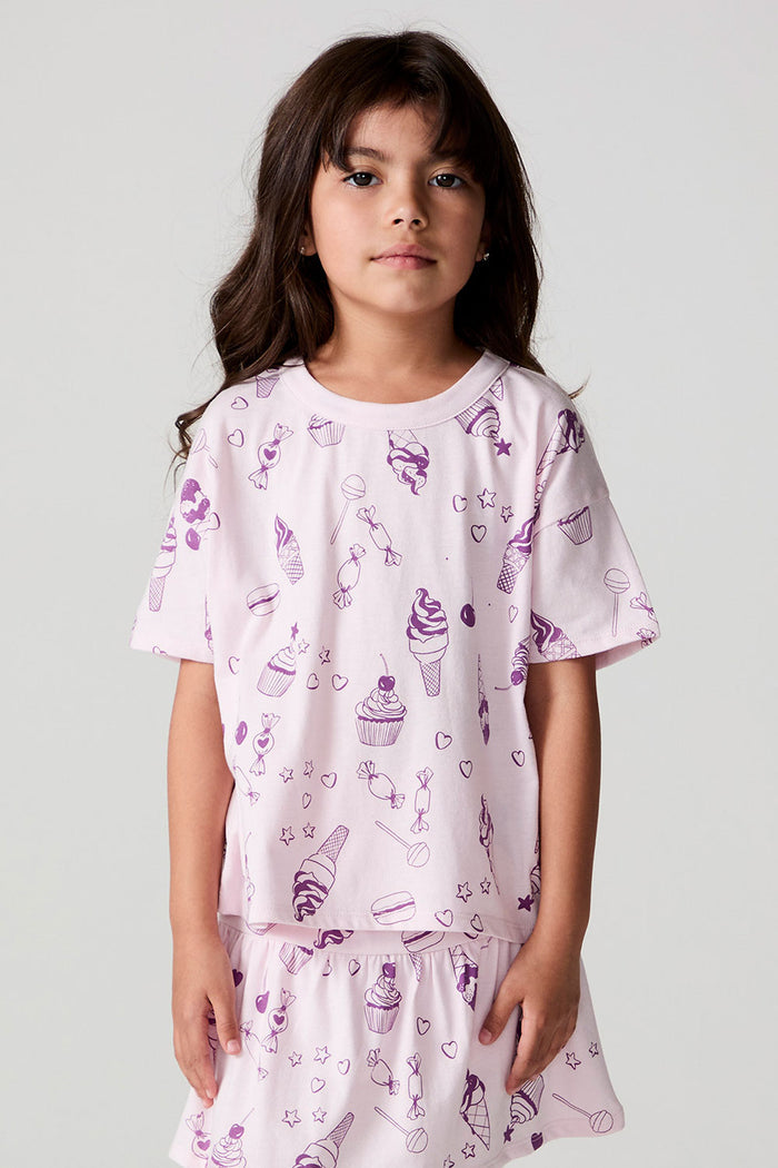 Front view of a girl wearing the Chaser Allover Sweets Tee on a neutral background