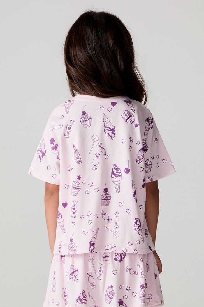 Back view of a girl wearing the Chaser Allover Sweets Tee and skort on a neutral background