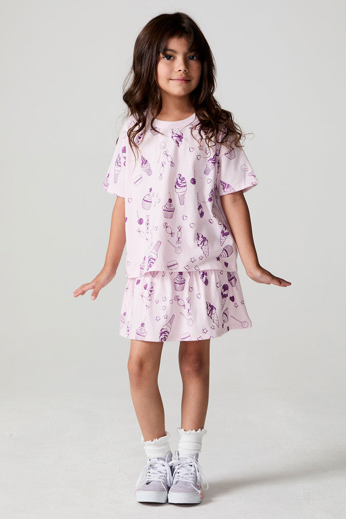 Full body front view of a girl wearing the Chaser Allover Sweets Tee on a neutral background