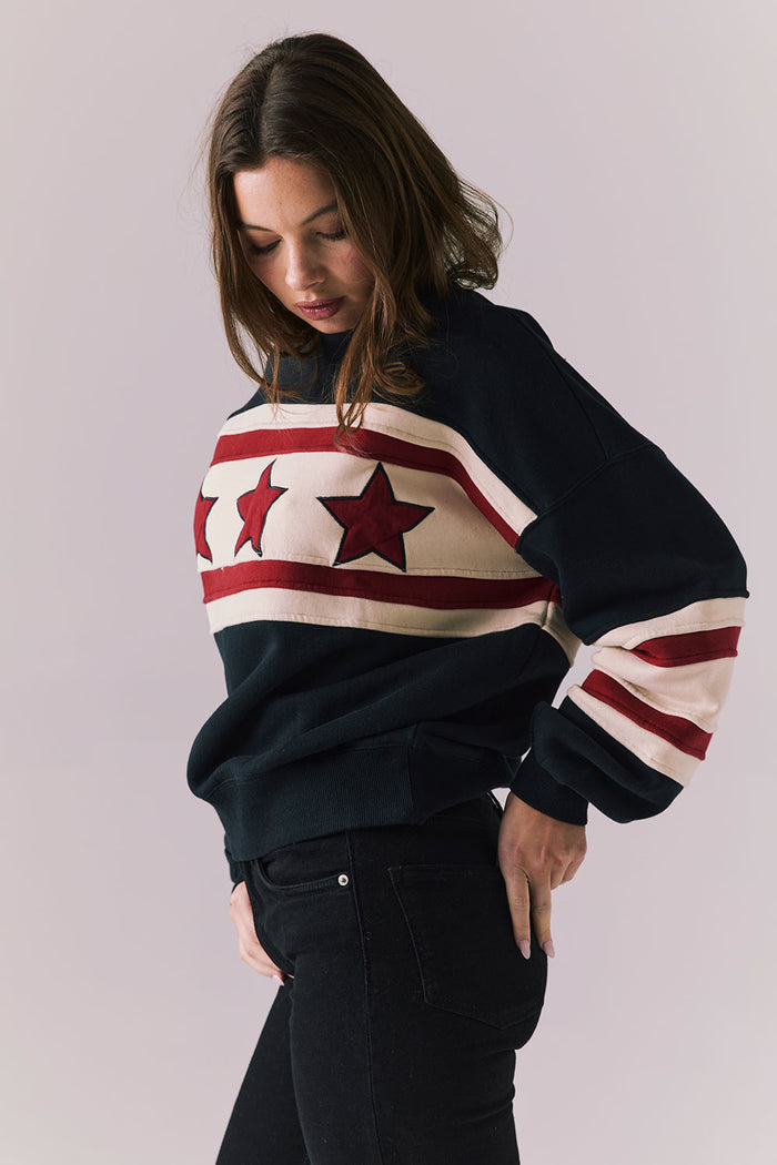 Woman wearing a black sweater with red and white star pattern on a plain background