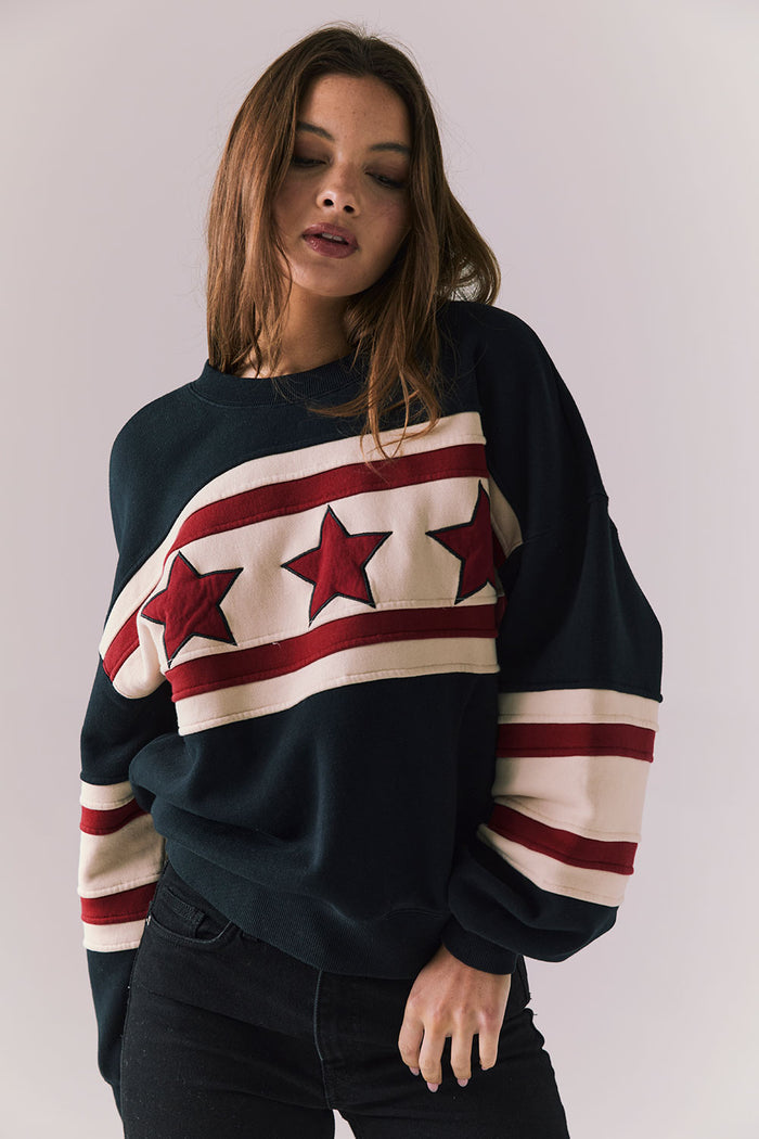 Woman wearing a sweater with star and stripe design on a plain background