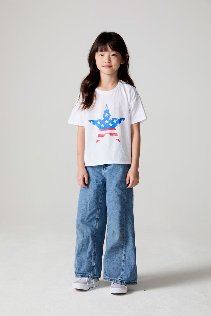 Full body front view of a girl wearing the Chaser  Americana Star Tee and jeans on a neutral background