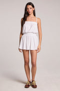 Front view of a woman wearing the Chaser  Angeline White Mini Dress and sneakers on a neutral background