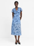 A woman wearing a blue, midi length, short sleeved V-neck dress with a floral pattern.
