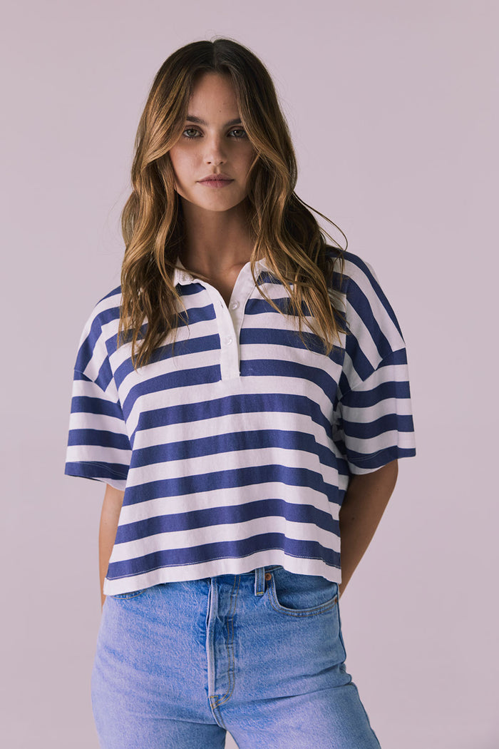 Woman wearing the Chaser Antoni Castaway Stripe Tee featuring wide navy and white stripes with a classic buttoned polo neckline