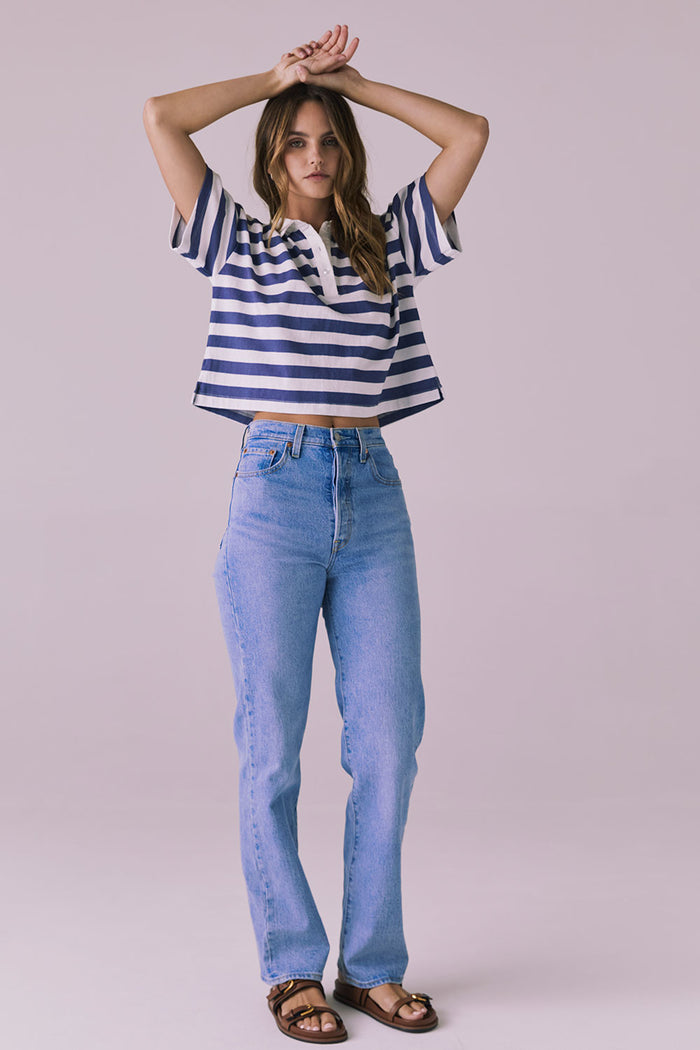 Woman wearing the Chaser Antoni Castaway Stripe Tee styled with high-waisted light-wash jeans and sandals in a minimalist studio setting