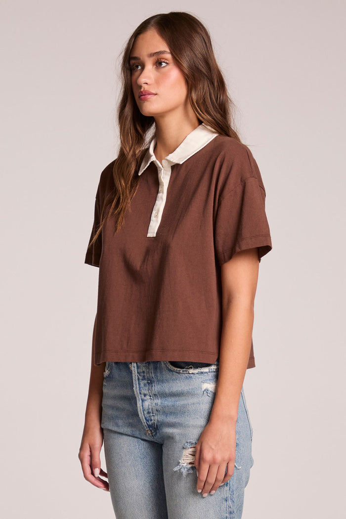 Side angle view of a woman wearing the Chaser Antoni Kahlua Tee on a neutral background with hands at her sides