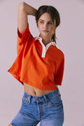 Woman wearing the Chaser Antoni Neon Flare Tee in bright orange with a contrasting white collar and buttoned neckline