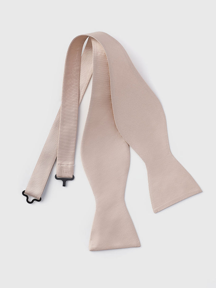 Apricot satin self-tie bow tie, untied and laid flat with adjustable strap, grey background.