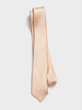 Apricot silk necktie folded and draped on a grey background.