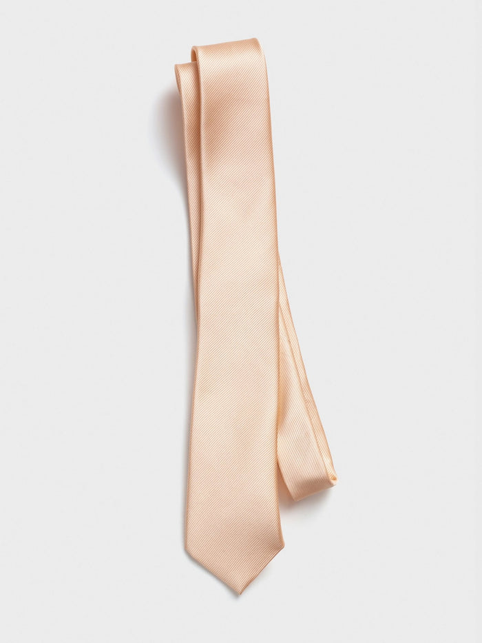 Apricot silk necktie folded and draped on a grey background.