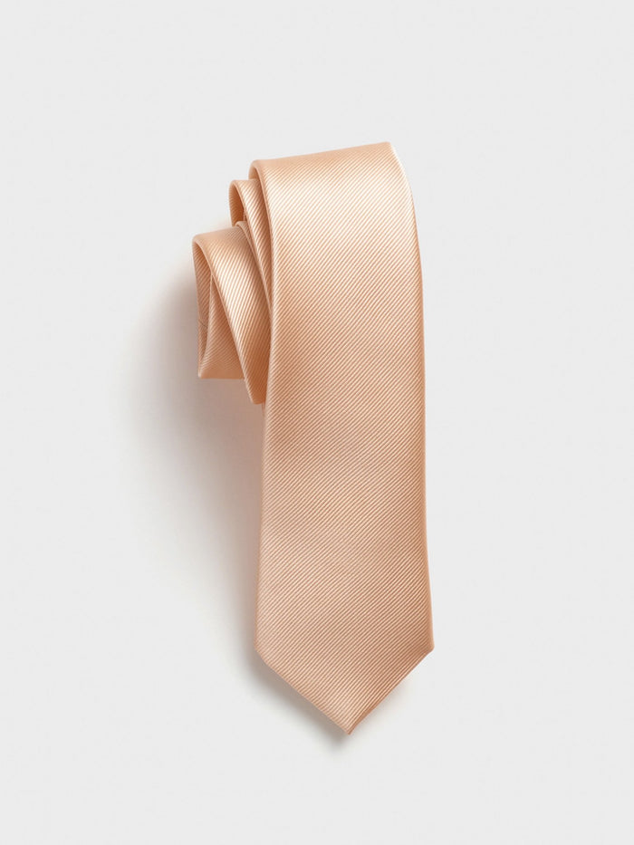 Apricot silk necktie with twill texture, rolled at the top, on a grey background.
