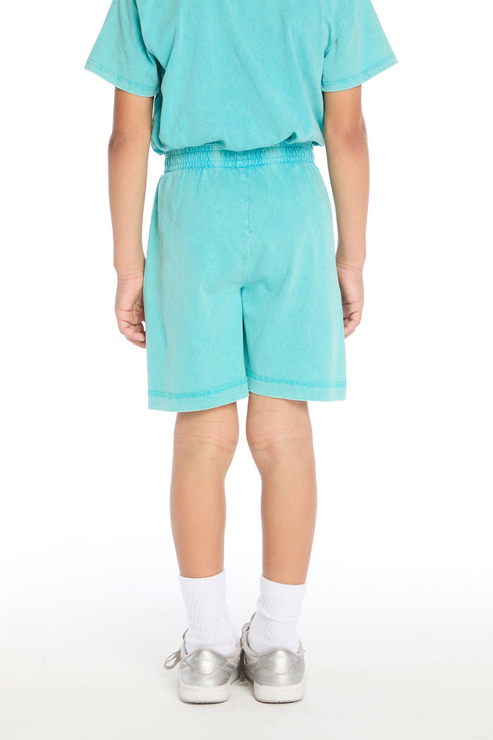 Back view of boy wearing the Chaser Kids Aqua Teal Cozy Beach Shorts with an elastic waistband, paired with the matching Aqua Teal Polo Shirt on a white background