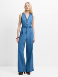 Woman wearing a blue denim sleeveless wide leg jumpsuit with a V neckline and metal button fastening
