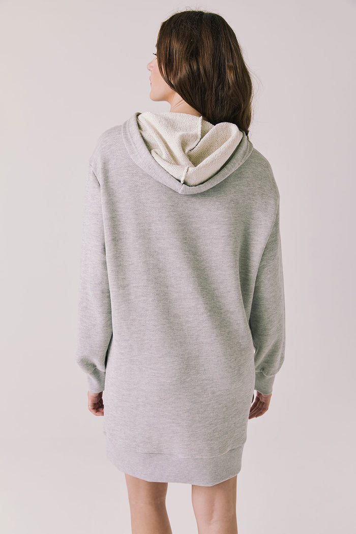 Back view of woman wearing Chaser's Aster Heather Grey Hoodie Dress on a plain background