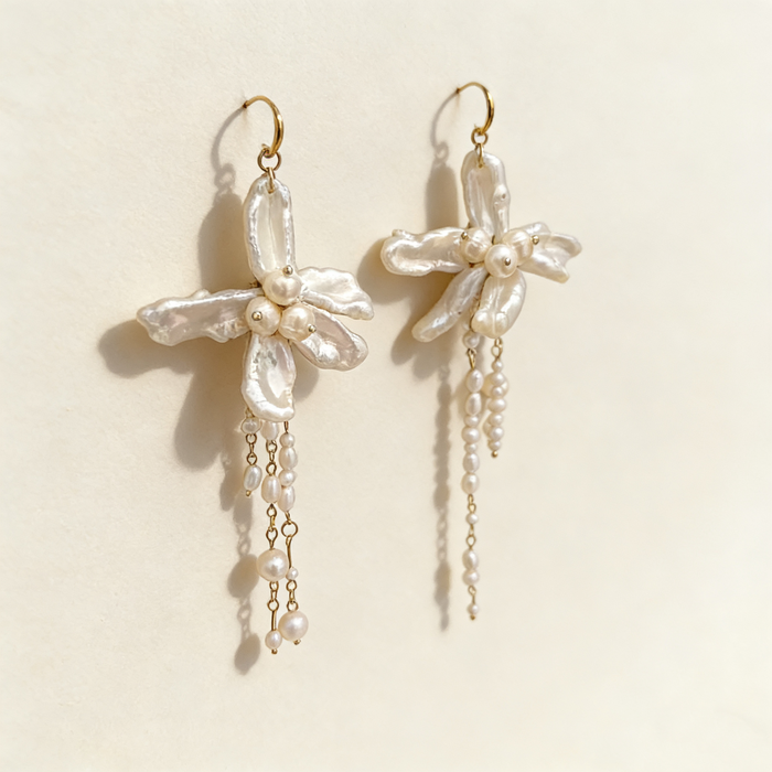 Handmade asymmetrical bridal earrings featuring freshwater baroque pearl flowers, pearl tassels, and 14K gold-filled French hooks.