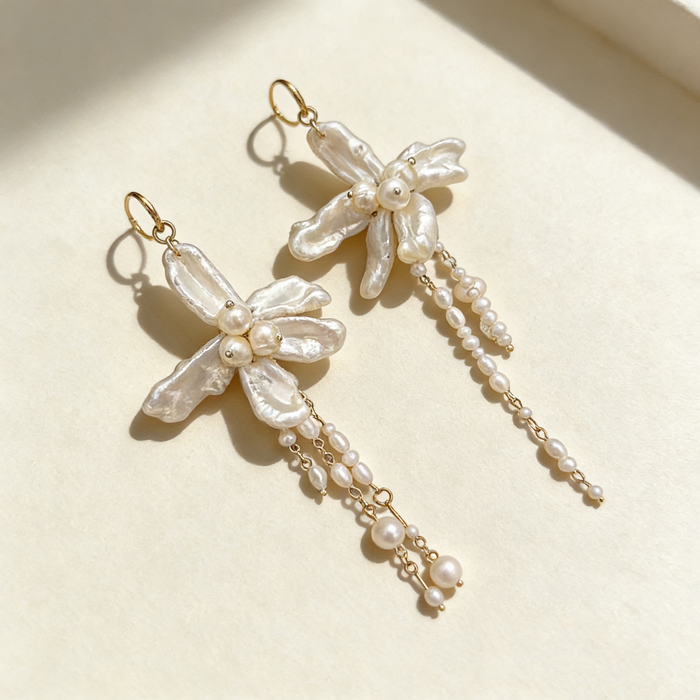 Handmade asymmetrical bridal earrings featuring freshwater baroque pearl flowers, pearl tassels, and 14K gold-filled French hooks.