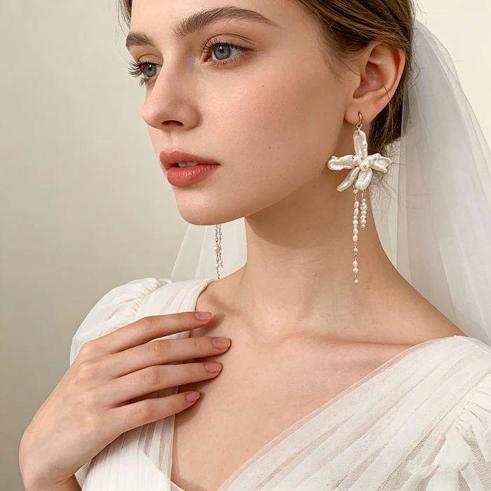 Handmade asymmetrical bridal earrings featuring freshwater baroque pearl flowers, pearl tassels, and 14K gold-filled French hooks.
