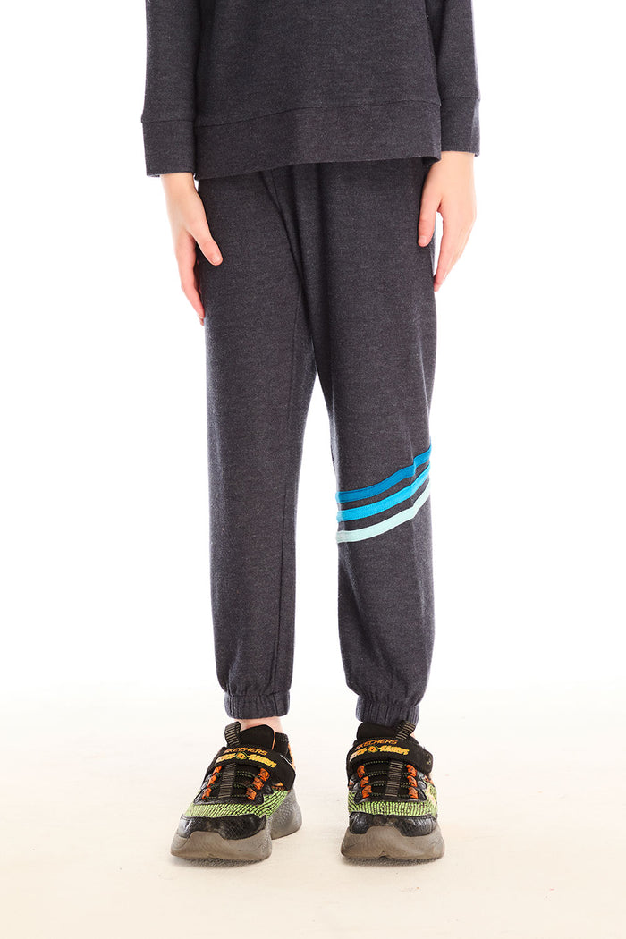 Boy wearing Chaser’s Avalon Lounge Pant with blue stripe strappings against a white background