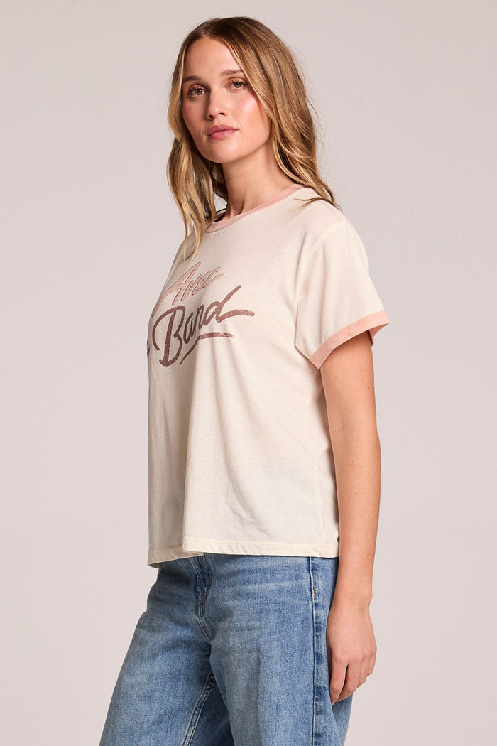 Side angle view of a woman wearing the Chaser  Avec Le Band Tee on a neutral background
